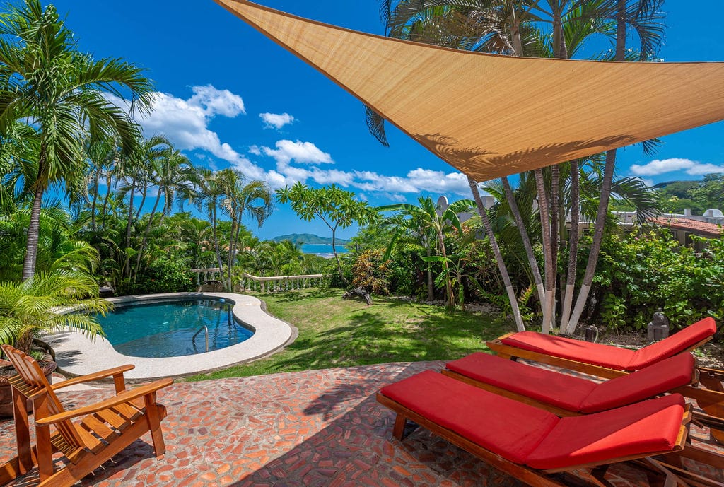 view of the ocean from a pool with chairs and sun loungers