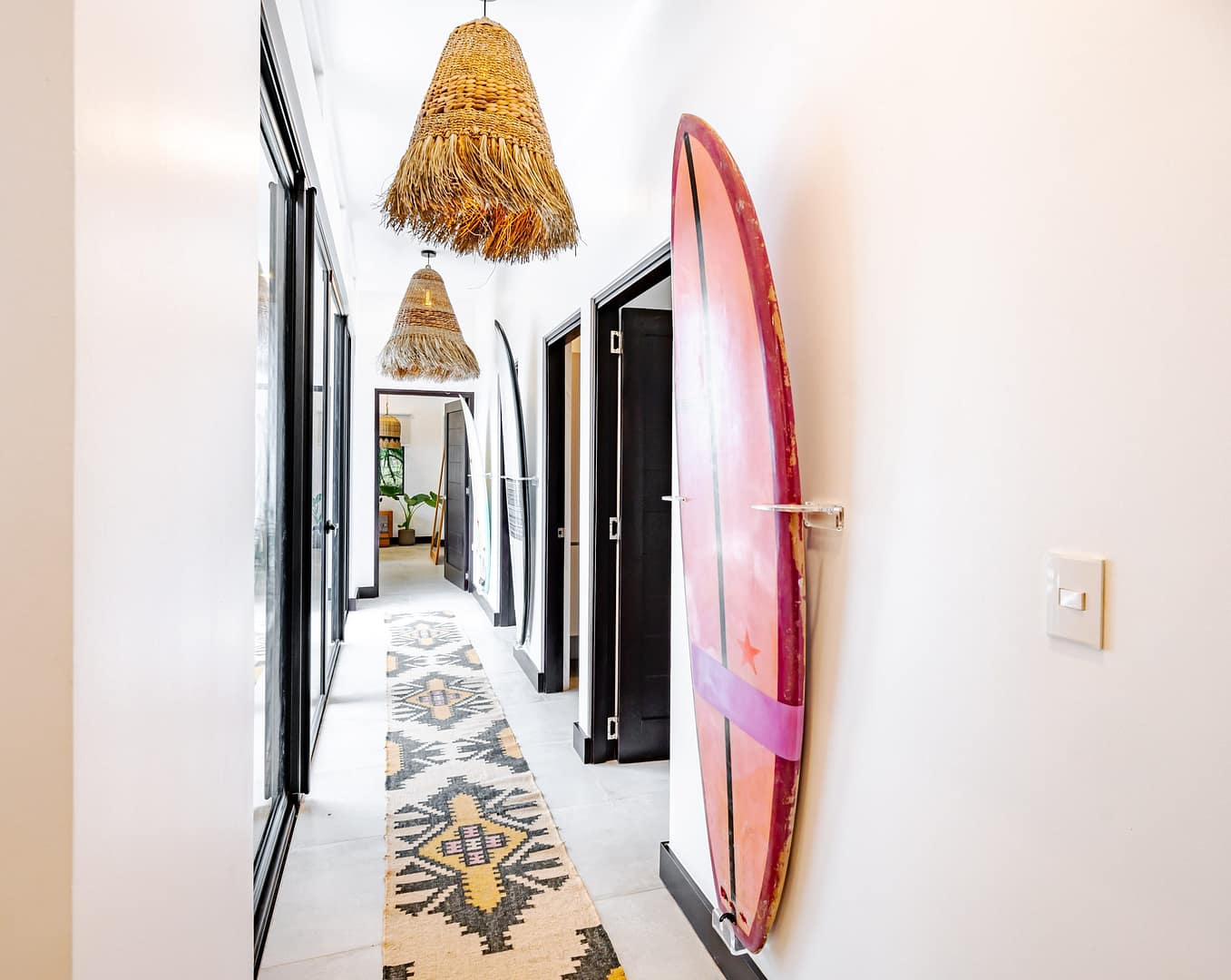 Hallway with tribal runner rug and surfboard wall art and raffia light pendents