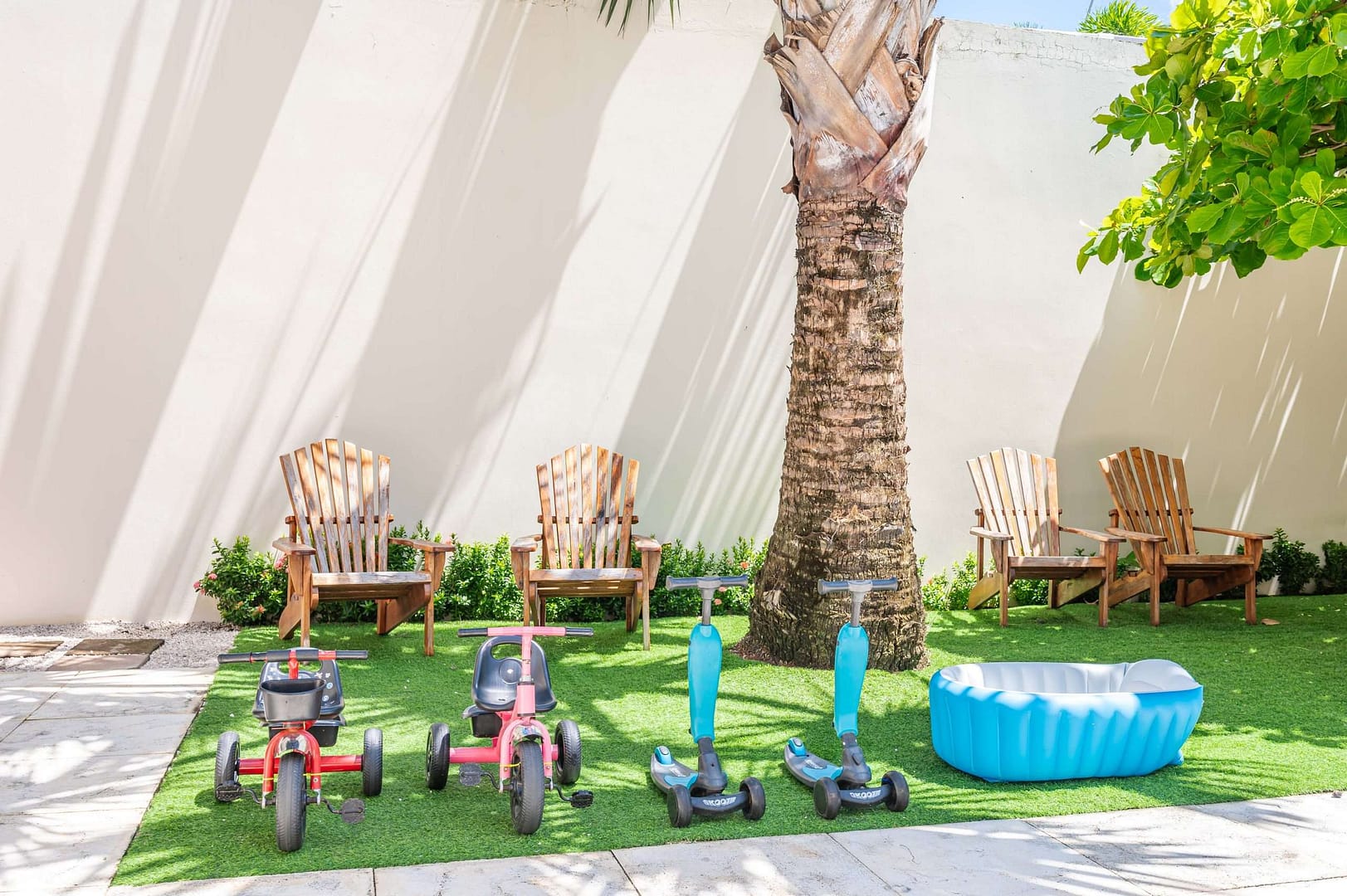 Kids outdoor toys and chairs in the shade of a giant palm in the private courtyard of Carolina del Mar in Langosta, Costa Rica.