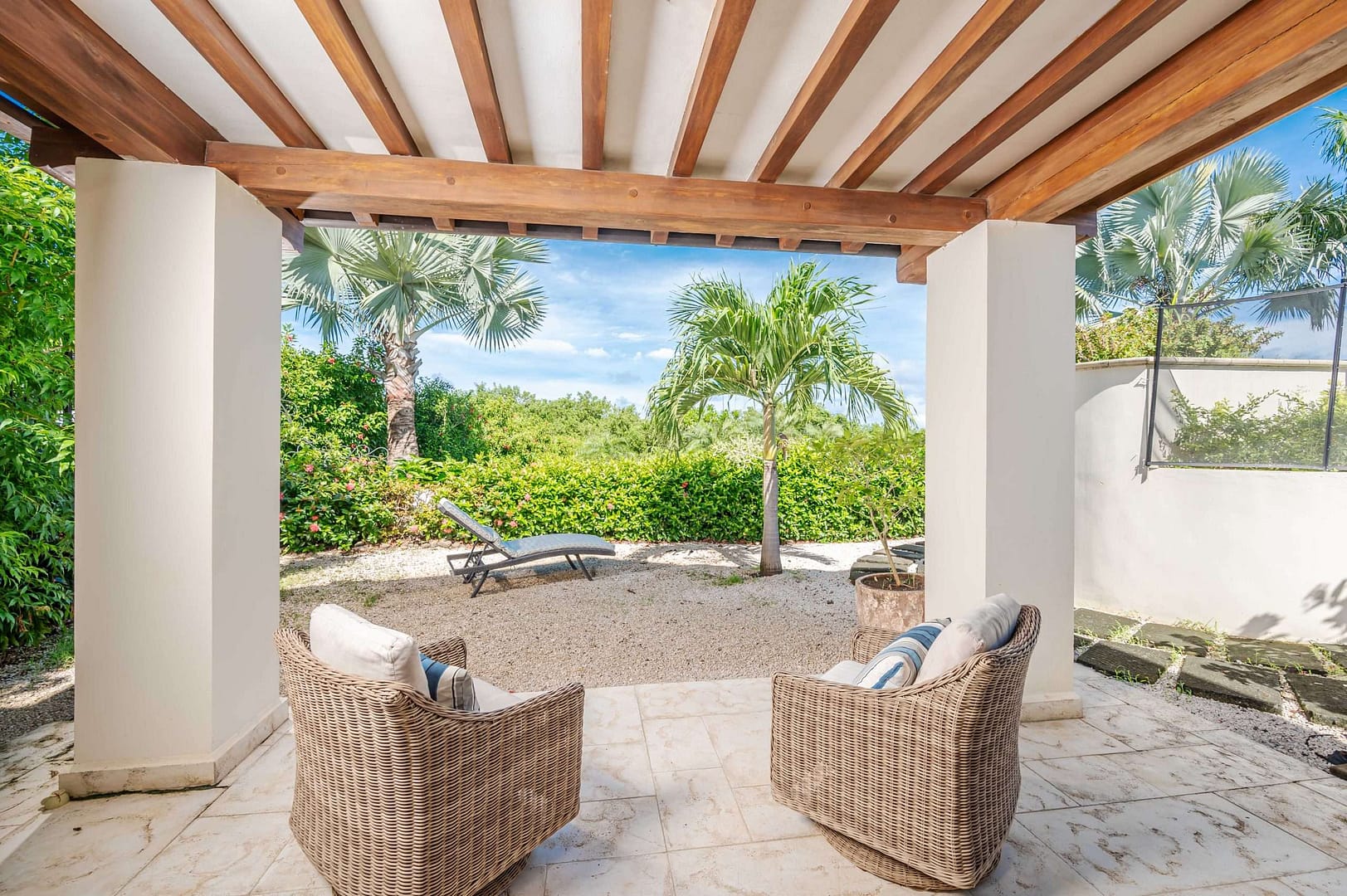 Carolina del Mar private outdoor patio sitting area with two cozy rattan arm chairs and a garden view.